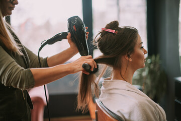 Hairdresser drying client hair at the salon