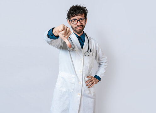 Doctor gesturing disapproval isolated. Unhappy doctor with thumb down isolated. Male doctor disapproving with fingers