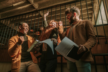 Three young, happy, overjoyed multiracial business partners celebrating after successfully made deal