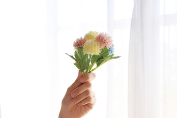 窓辺で花束を持つ女性の手
