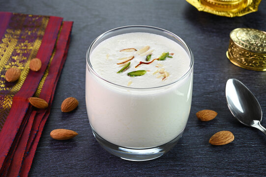 Sweet lassi served in a glass cup garnished with saffron, almonds and pistachios.