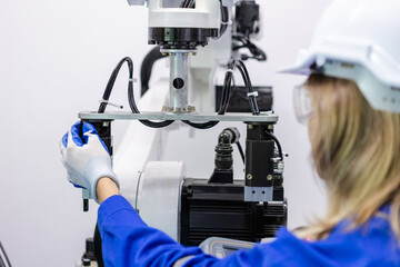 Close up robot arm, female technician engineer using remote control automation robotics at industrial modern factory. woman working at factory innovation automation robot.