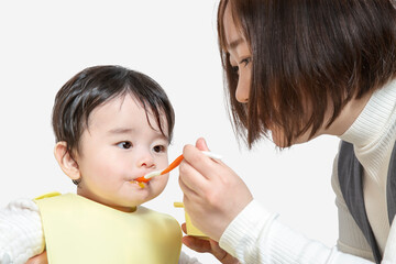 赤ちゃんに離乳食を食べさせる母親。育児、離乳食、子育てイメージ