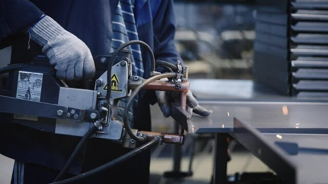 A factory worker uses spot welding to join steel parts. The process of manufacturing steel products.