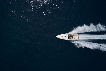 Large speed boat moving at high speed. Top view of a white boat sailing to the blue sea. Travel - image.Drone view of a boat sailing. Motor boat in the sea.