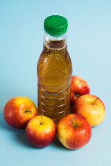 Apple juice in a plastic bottle and red apples on a blue background. Earth day, zero waste and plastic recycling concept.