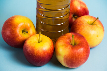 Apple juice in a plastic bottle and red apples on a blue background. Earth day, zero waste and plastic recycling concept.