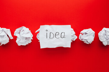 sheet of paper with word idea and crumpled paper balls on red background. Brain storming and idea...