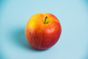 Juicy red yellow apple on a blue background. Concept of earth day, zero waste and plastic recycling.
