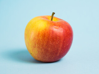 Juicy red yellow apple on a blue background. Concept of earth day, zero waste and plastic recycling.