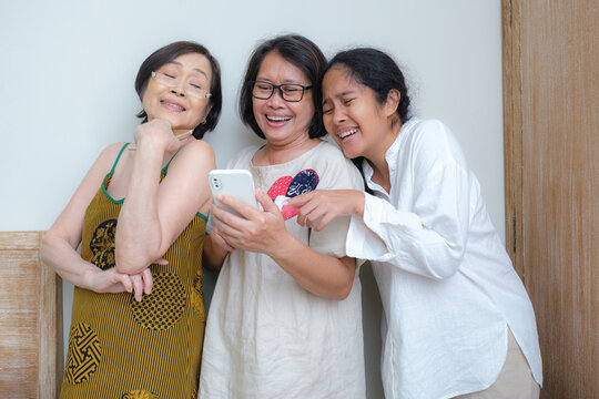 Three Indonesian women are video calling, laughing.