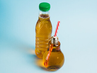 Juice in a plastic bottle and drink in a reusable glass bottle on a blue background. Concept of earth day, zero waste and plastic recycling.