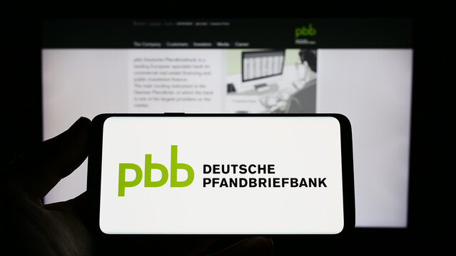 Stuttgart, Germany - 04-01-2023: Person holding smartphone with logo of company Deutsche Pfandbriefbank AG (PBB) on screen in front of website. Focus on phone display.