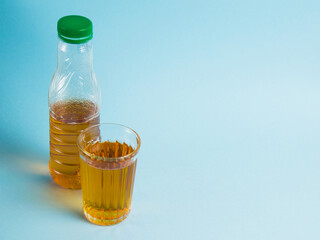 Glass of juice and plastic bottle on blue paper background. Concept of earth day, zero waste and plastic recycling.