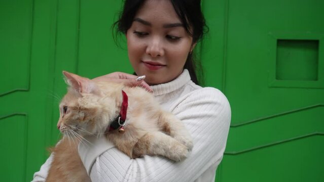 A beautiful Asian woman is carrying her orange Angora cat