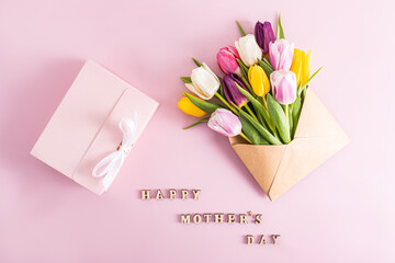 a festive composition for Mother's Day. Beautiful colorful spring tulips in a craft envelope and a pink box with a gift. top view. text.