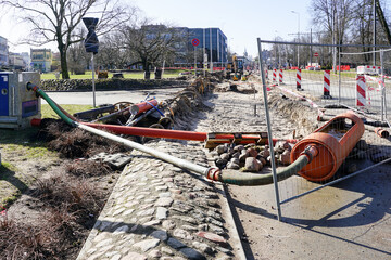 Street repair works site dewatering system with water pump, pipes and hoses