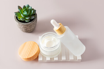 organic cosmetics with natural ingredients in a matte white jar and a bottle with a dispenser on a white plaster podium. light background.