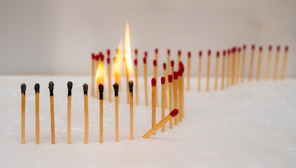 Row of burning matches and all matches on white background. spread of fire one match isolated to...