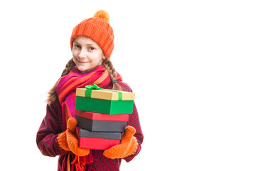 Winsome Happy Caucasian Little Girl In Orange Beanie Hat, twirling Scarf and Mittens With Pile of Colorful Giftboxes. Isolated Against Pure White