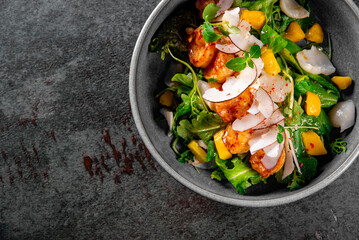 Shrimps salad with arugula, mango and coconut in bowl