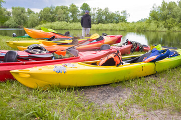 Line of Colorful Plastic Kayaks Placed Together For Drying on Grass Outdoors.