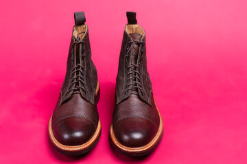 Pair of Premium Dark Brown Grain Brogue Derby Boots Made of Calf Leather with Rubber Sole Placed Over Pink Background