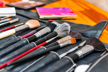 Fototapeta premium Line of Variety of Professional Makeup Tools and Brushes With Eye shadows Placed as Make-up Products Set
