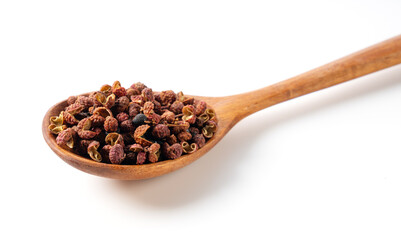Sichuan pepper and wooden spoon set against a white background.