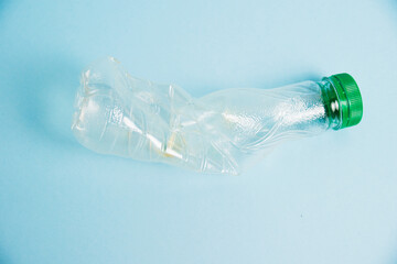 Used plastic bottle of juice for a drink on a blue background. Concept of earth day, zero waste and plastic recycling.