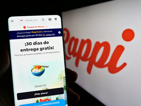 Stuttgart, Germany - 04-02-2023: Person holding cellphone with webpage of Colombian food delivery company Rappi Inc. on screen in front of logo. Focus on center of phone display.
