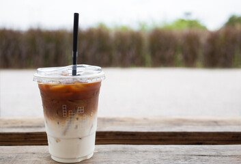 Iced of latte coffee cup on wooden backdrop grass nature background. Copy space for text