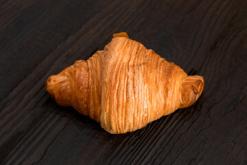 One croissant on a wooden cutting board. Rustic dark table. Food banner. Tasty fresh croissant, jam, orange juice. Continental breakfast served with freshly baked pastry. Close up view, Good morning