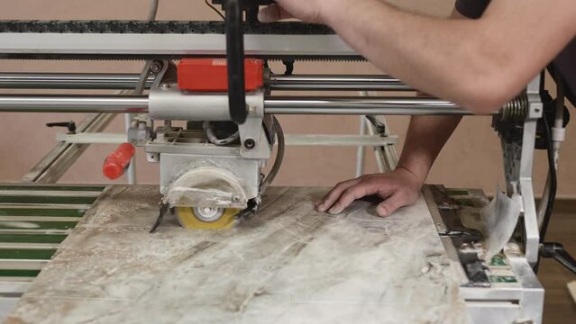 The process of cutting porcelain stoneware slabs with a hydraulic cutter. Preparation of tiles for laying on walls or floors.
