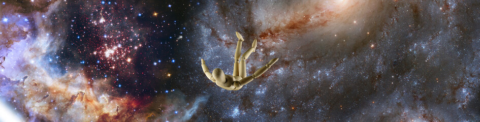 Fototapeta na wymiar wooden mannequin falling in space against the background of a starry space landscape