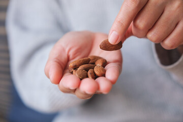 Closeup image of hands holding and picking up an almonds