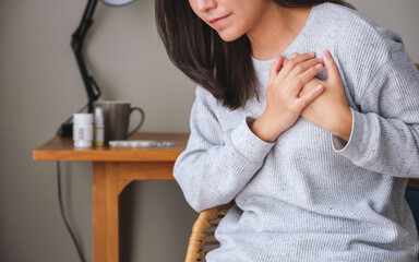 Closeup image of a woman with hands on chest, sudden heart attack, suffering from chest pain