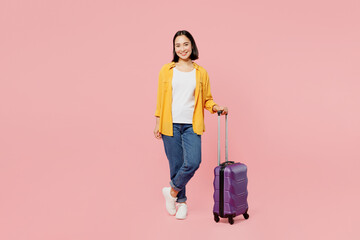 Full body traveler smiling woman wear casual clothes hold suitcase bag isolated on plain pastel pink background. Tourist travel abroad in free spare time rest getaway Air flight trip journey concept.