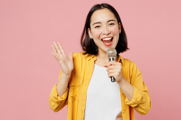Young singer smiling woman of Asian ethnicity wear yellow shirt white t-shirt sing song in...