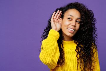 Young curious nosy woman of African American ethnicity wears casual yellow sweater try to hear you...
