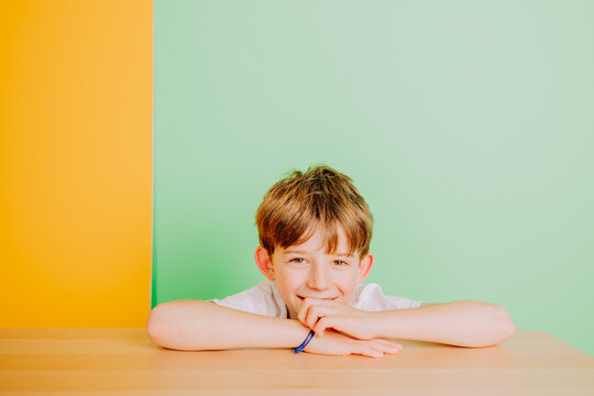 Enfant espi&egrave;gle qui rigole derri&egrave;re un banc en studio