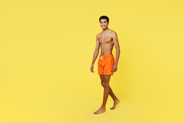 Full body side profile view smiling young sexy man wear orange shorts swimsuit relax near hotel...