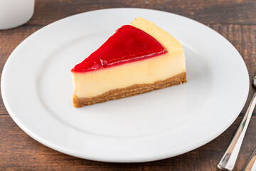 Delicious strawberry cheesecake with coffee next to it on wooden table