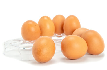 Chicken eggs in a tray. Several eggs lie next to the tray. Eggs are isolated on a white background.