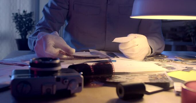Photo search for a suspect at the KGB police table. Hands in white gloves hold documents. Dark worker's room. CZ, Kladno, Polska, 8.3.23
