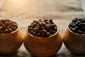 Roasted coffee beans in a ceramic pots on burlap background. Rustic style banner for coffee shop window.