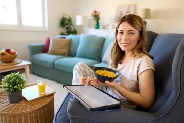 Smiling woman with digital tablet and breakfast at home