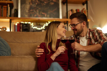 Romantic young couple relaxing at home and drinking red wine