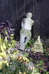 Ancient style worn decorative sculpture abandoned in the garden. Selective focus.