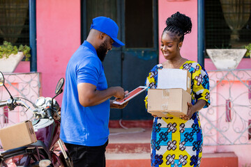 African Delivery Courier Man from Local Postal Shipping Service delivers Mail packages with motorcycle to Female Customer at Home.